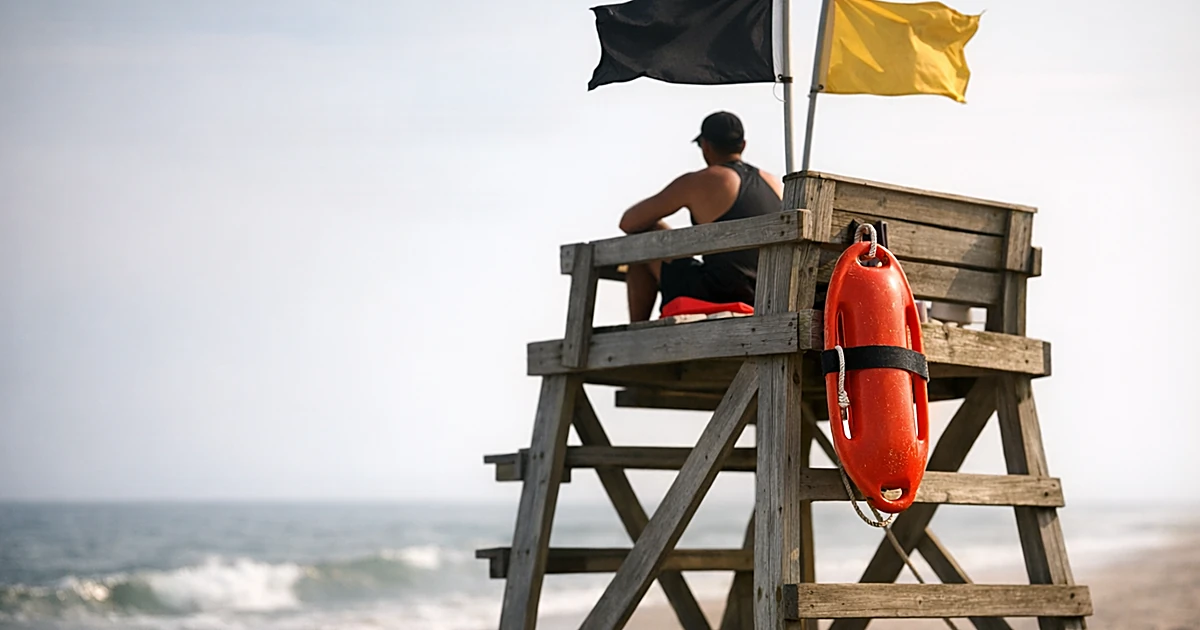 Lifeguard stand with rescue buoy at empty beach with ocean in background during summer heat